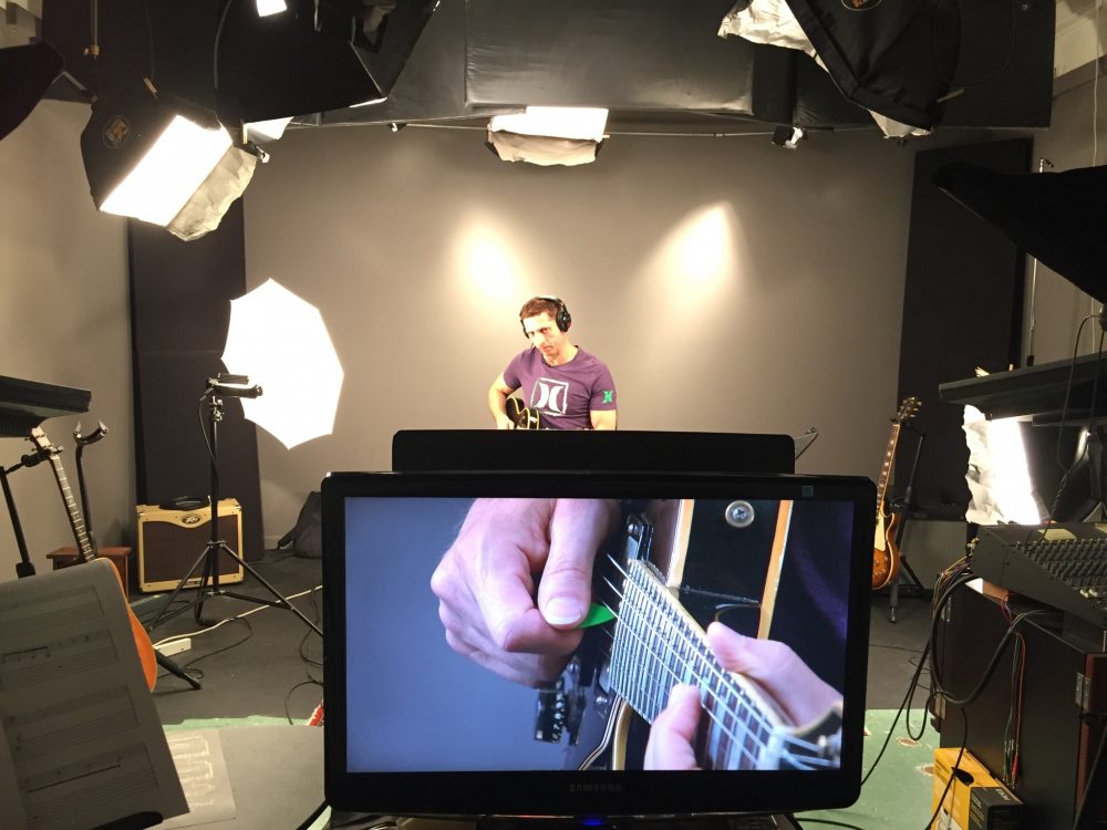 Man with guitar recording online guitar lessons